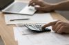 Foto: Person tippt auf Laptop und Taschenrechner